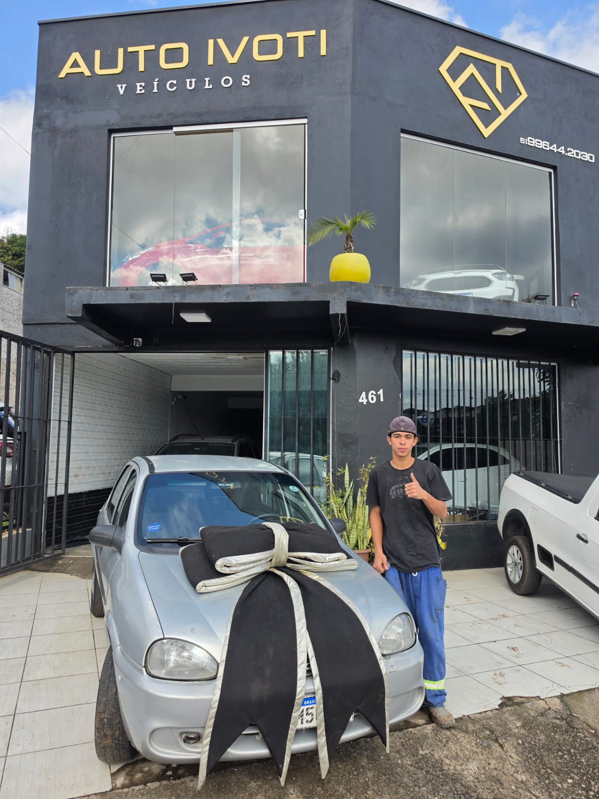 Cliente ao lado do hatch prata com laço de entrega