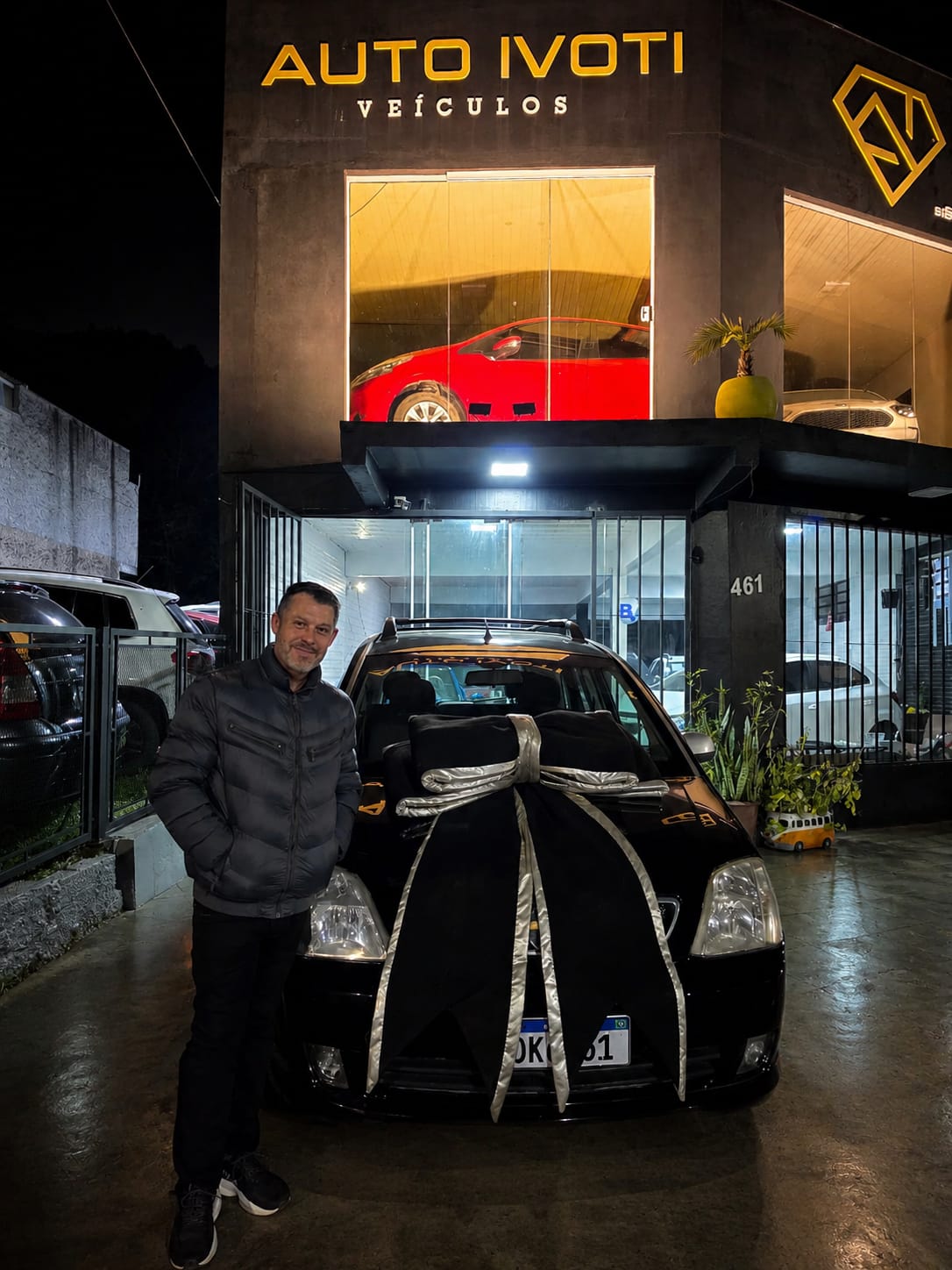 Cliente ao lado do seu carro entregue à noite na loja