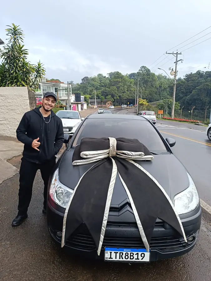 Cliente recebendo as chaves do sedã preto com laço de entrega