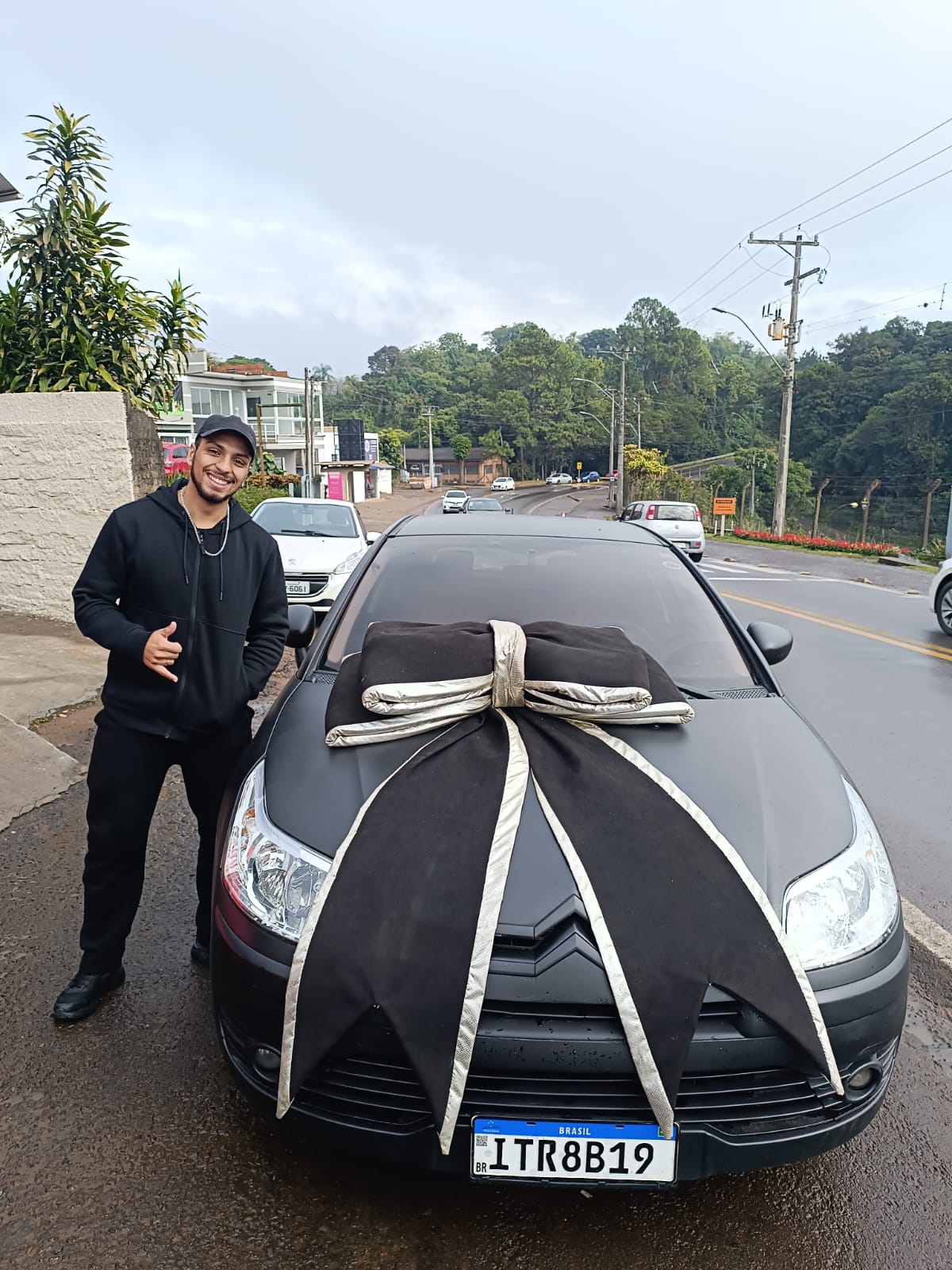Cliente recebendo as chaves do sedã preto com laço de entrega
