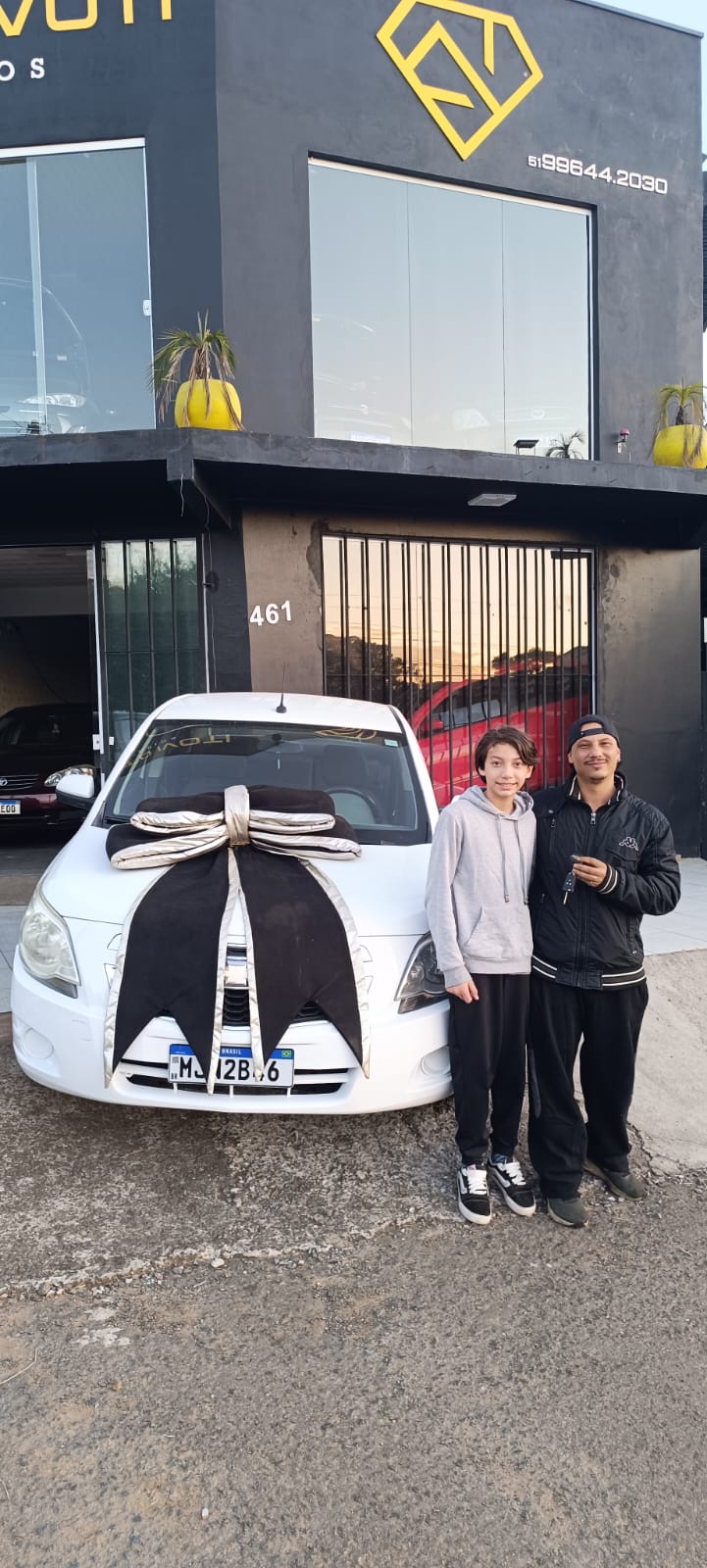 Pai e filho recebendo as chaves do carro branco
